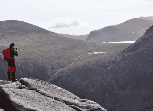 A view of a rock climber looking at mountains